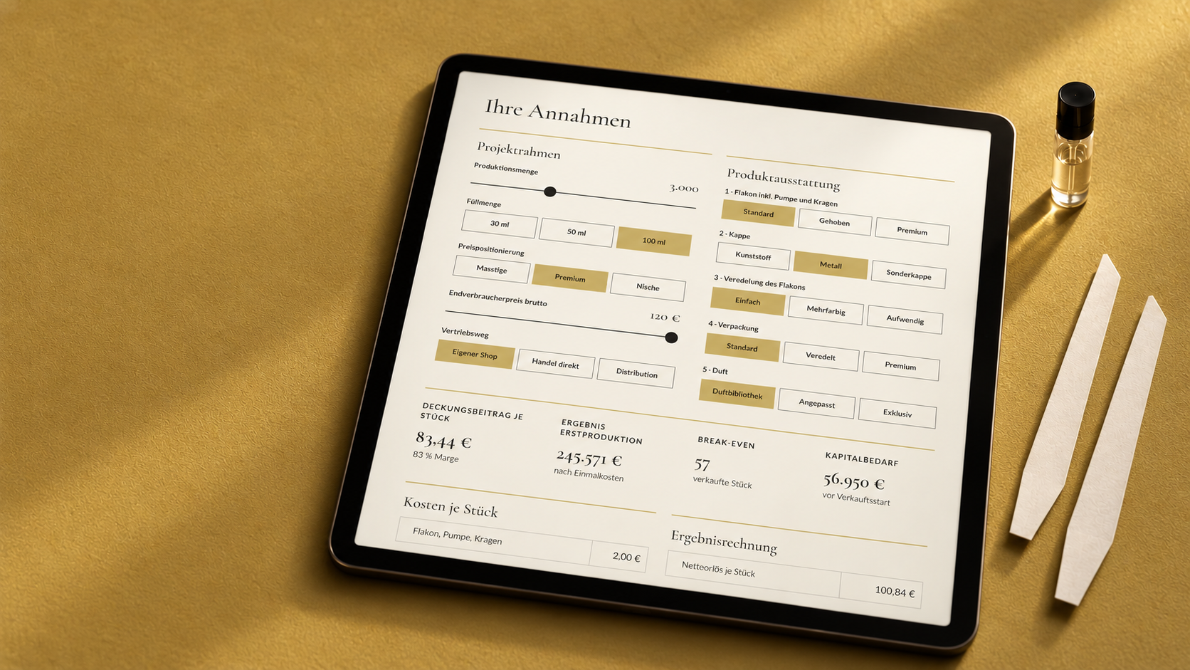 Tablet mit dem Parfum-Kalkulator auf einer matten Goldfläche; daneben zwei Duftstreifen und ein unbeschriftetes Probenfläschchen.